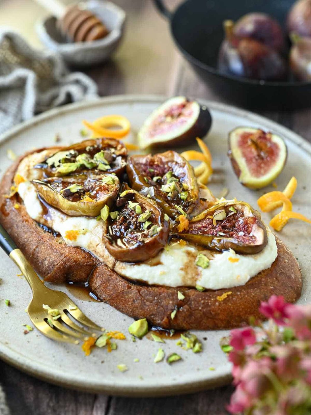 Fig toast on a beige plate with fresh figs in the background.