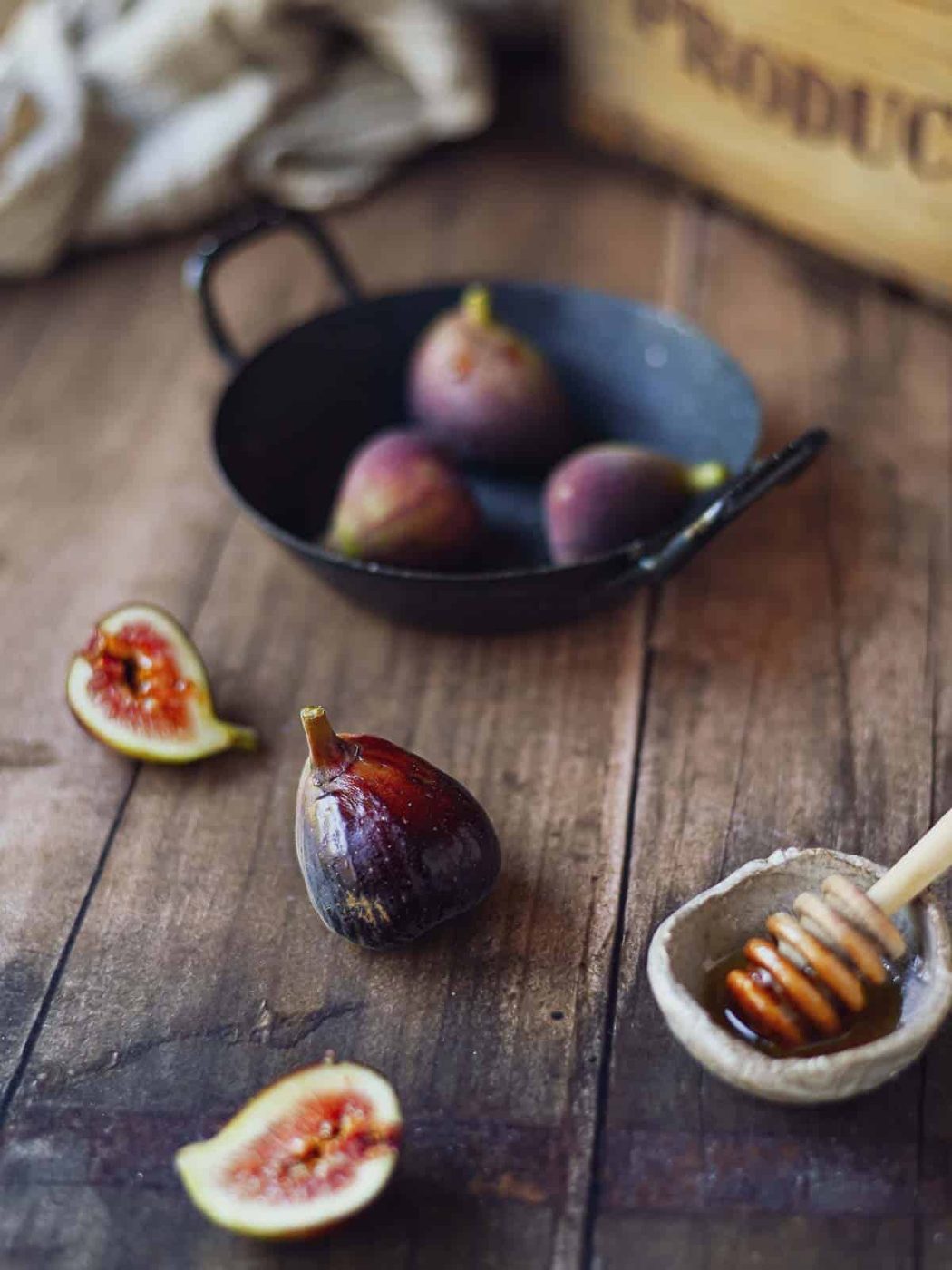 Figs in a roasting pan on a wood surface.