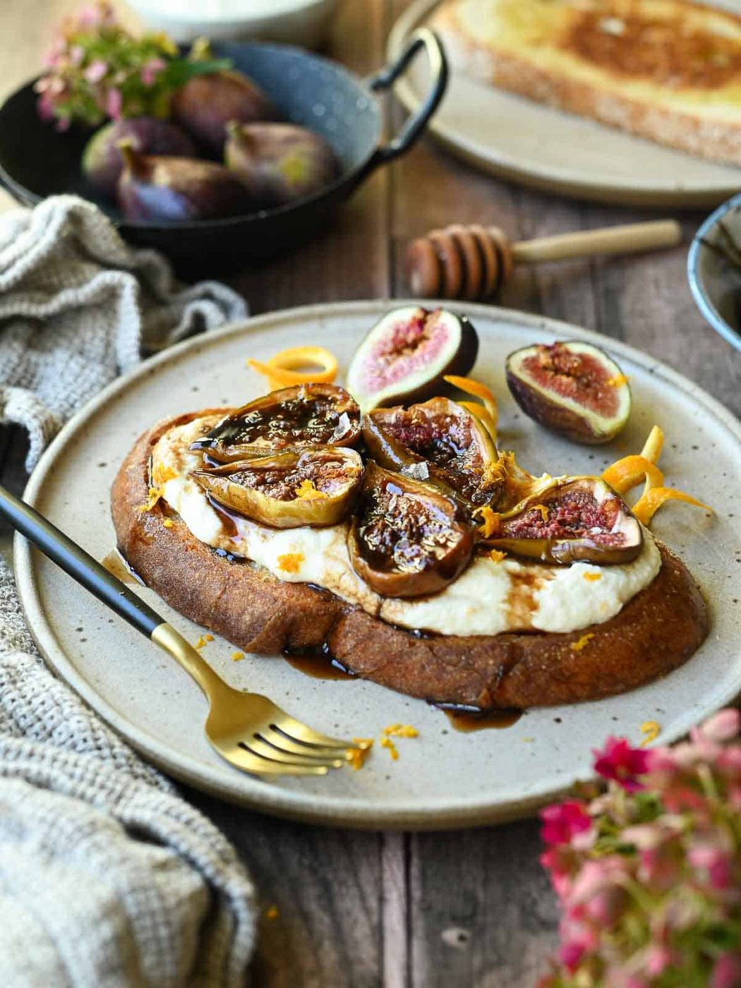 Balsamic roasted fig toast on a beige plate with orange zest and fresh figs.