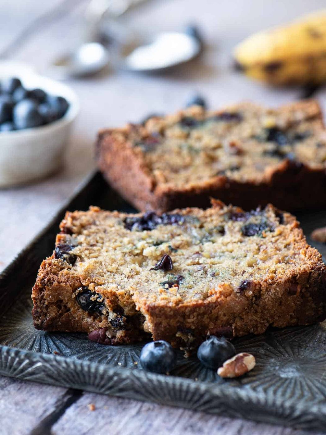 Two slices of banana blueberry bread on a metal pan.