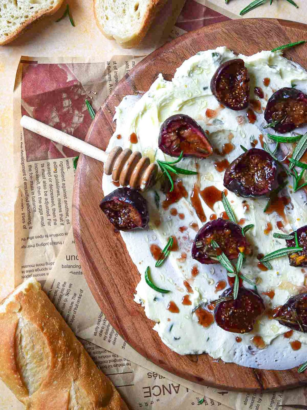 Figs and butter on a round wooden board with a honey stick.