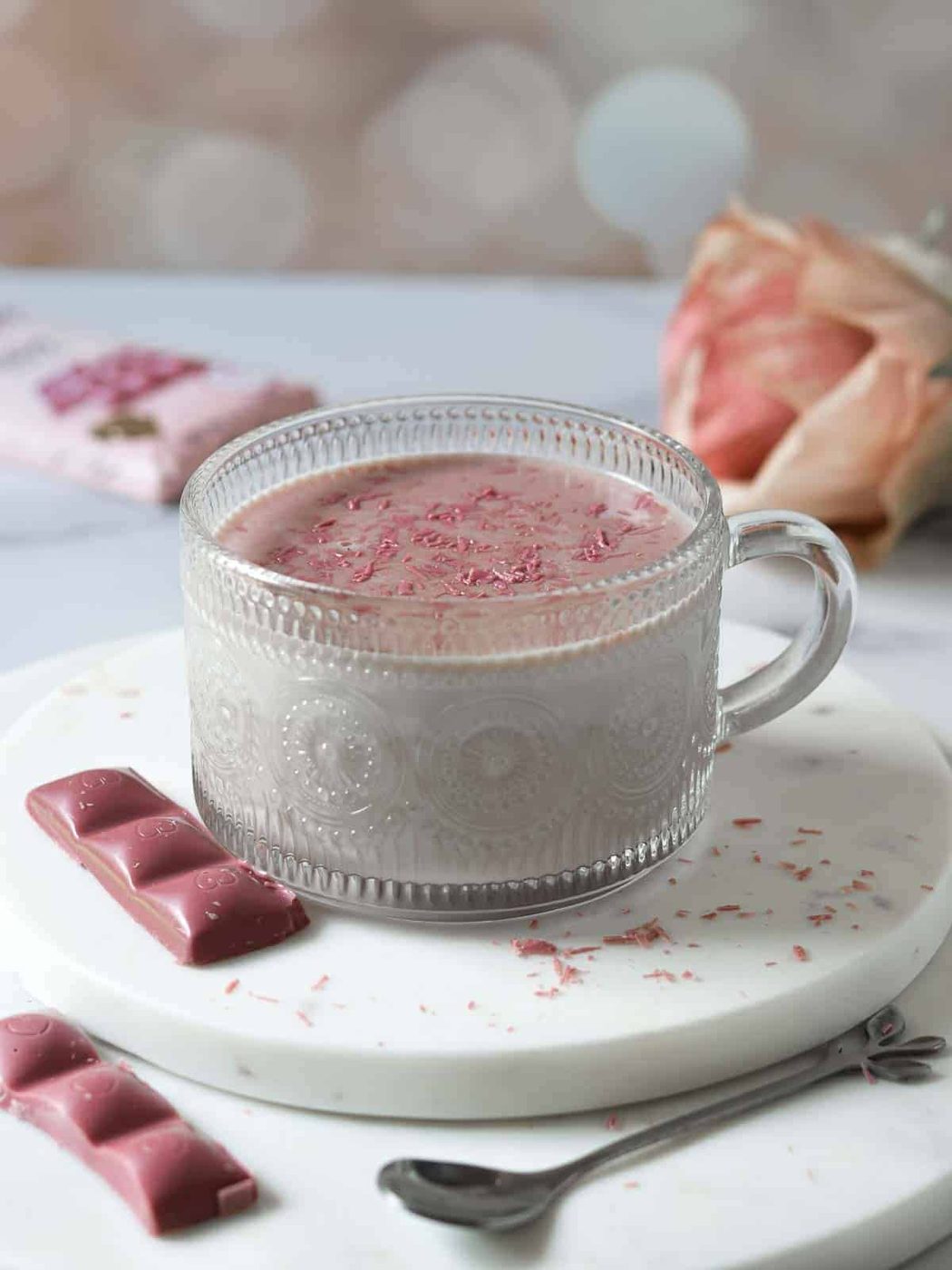 Ruby hot chocolate in a clear mug on a white surface.