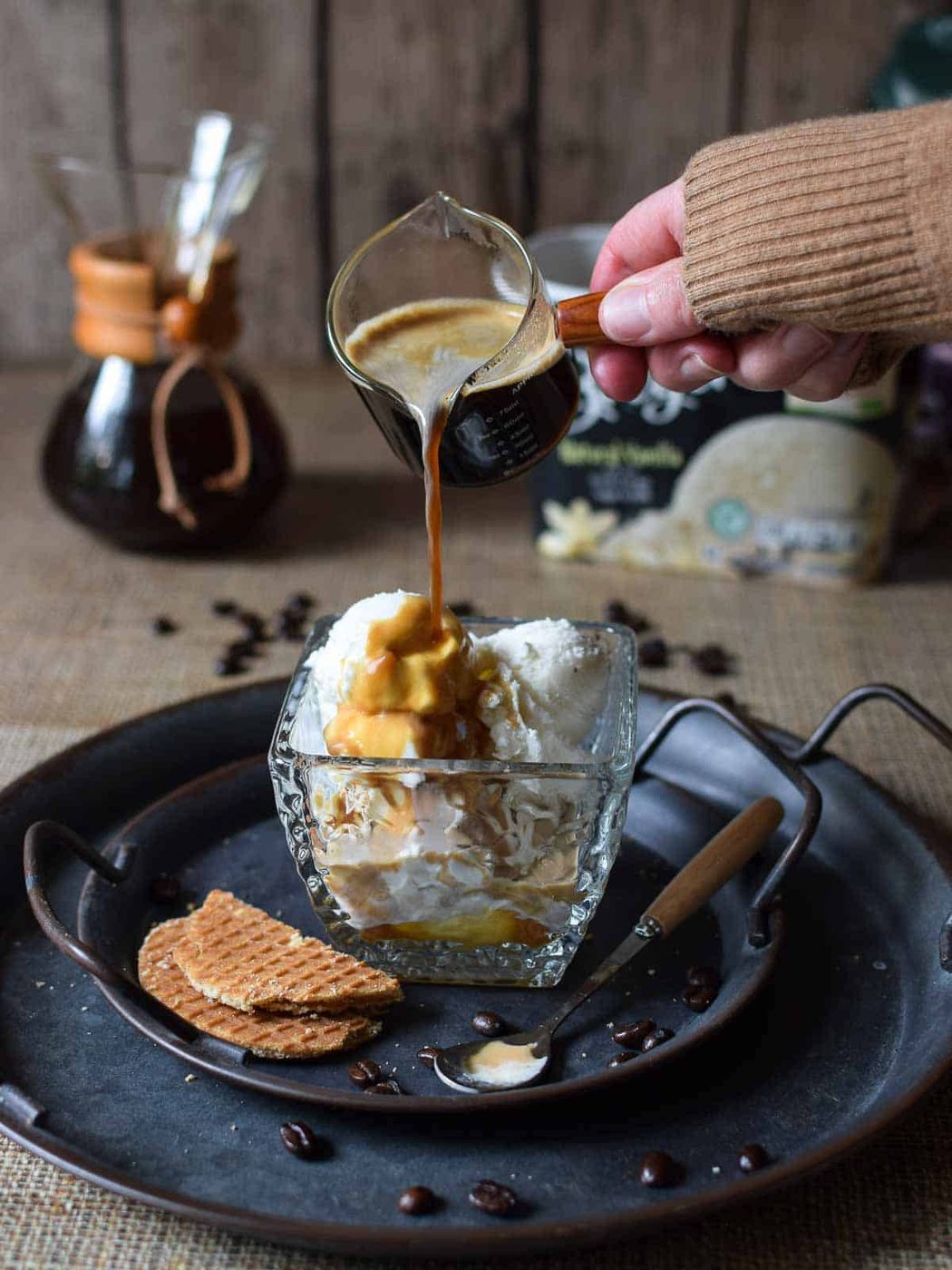 Espresso being poured over vanilla ice cream on a grey and brown surface.