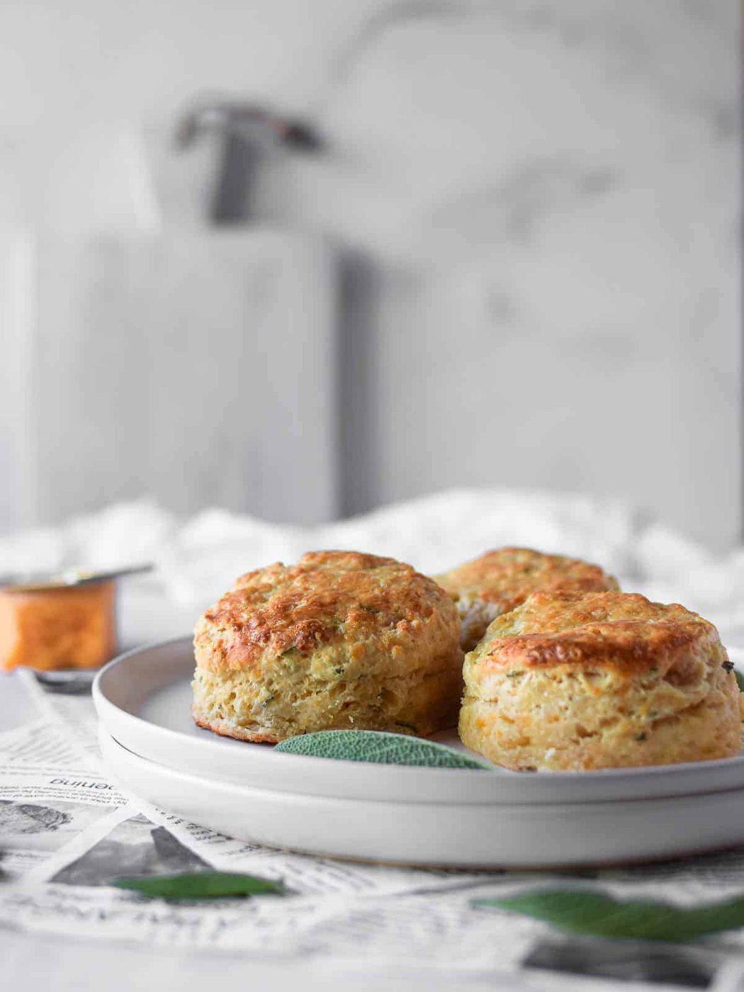 Three cheddar and sage biscuits on a white plate.