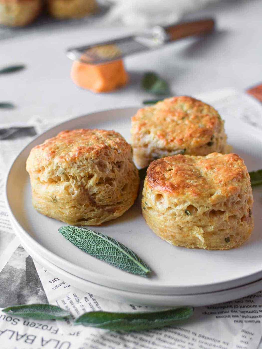 Three biscuits on a white plate with cheese.