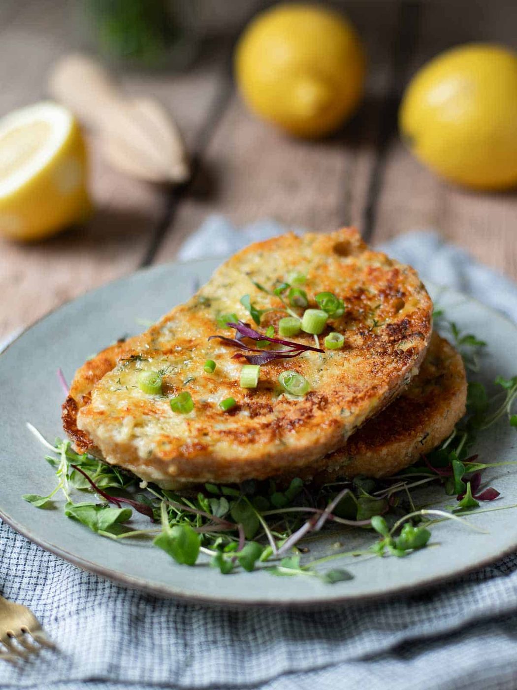 Angled view of savory French toast on grey plate with lemons in the background.