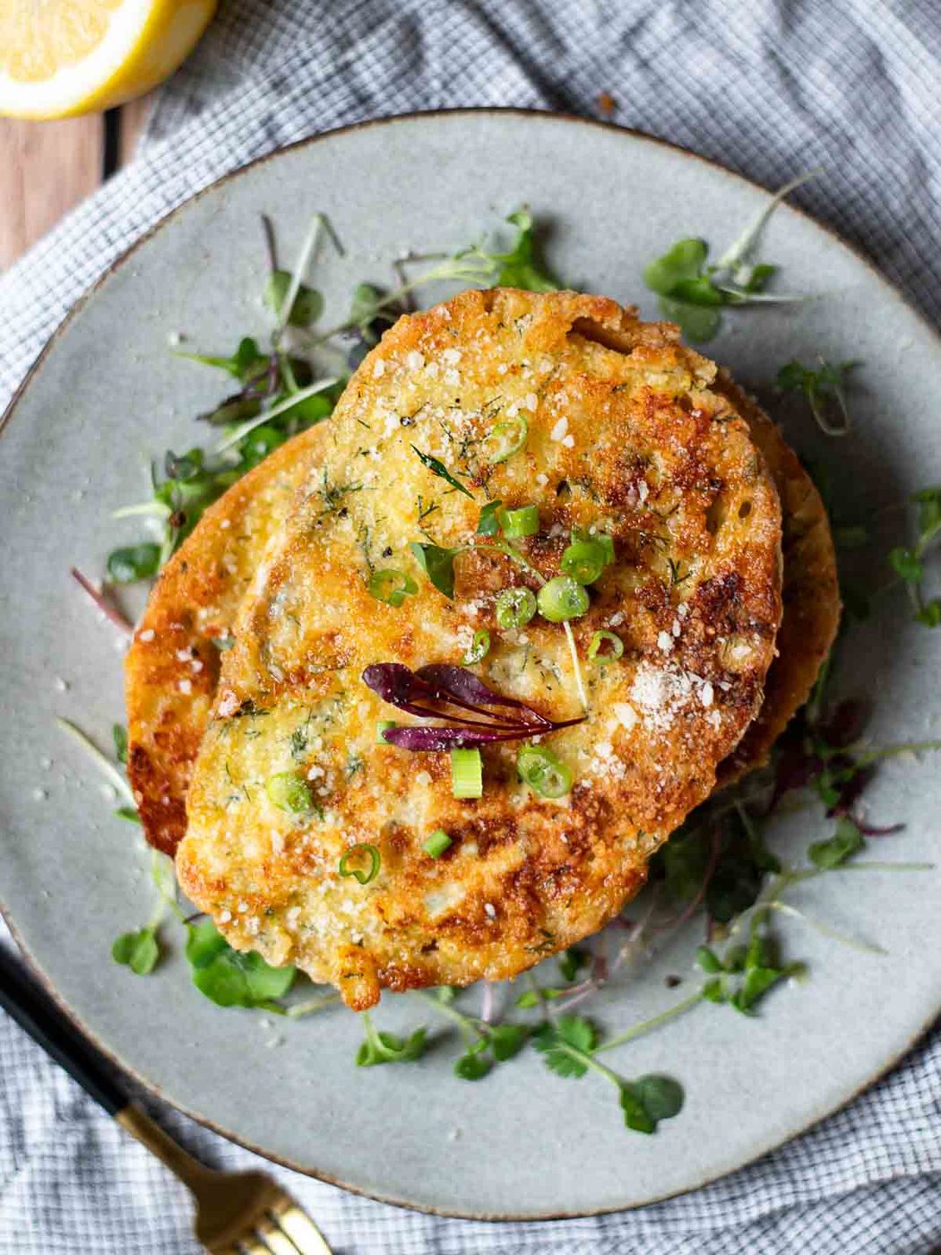 Overhead of savory French toast over a bed of microgreens on a grey plate.