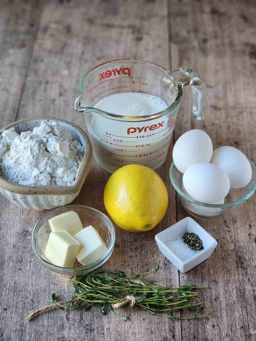 Ingredients for lemon-thyme popovers on a wood surface.