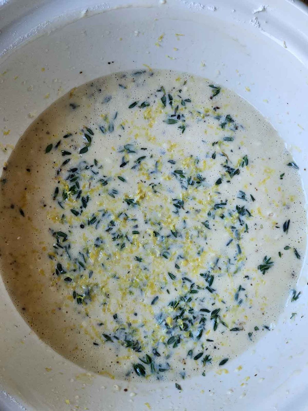 Overhead of lemon thyme popover batter in a large bowl.