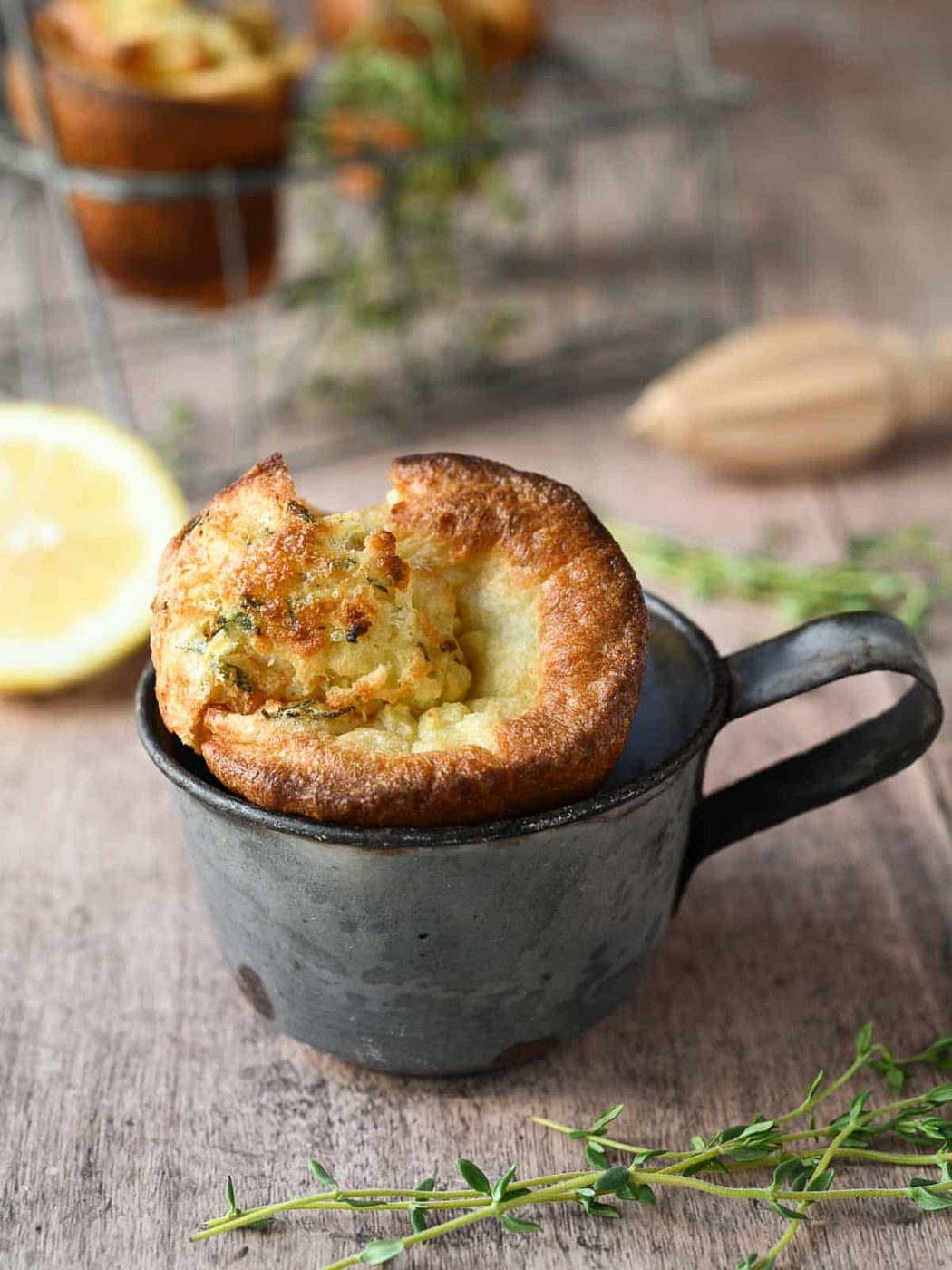 One popover in a vintage metal cup with thyme and lemons on the background.