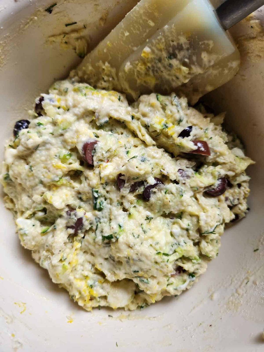 Mixed zucchini batter in a bowl with a spatula.