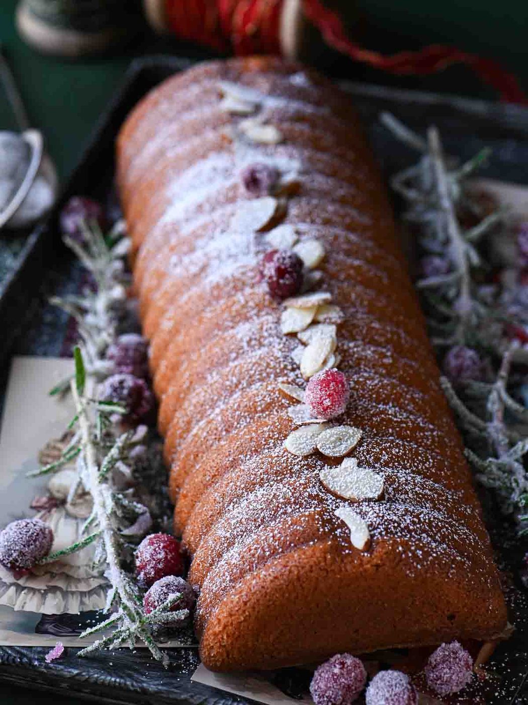 Almond cake close-up with almonds, cranberries and sugared rosemary.