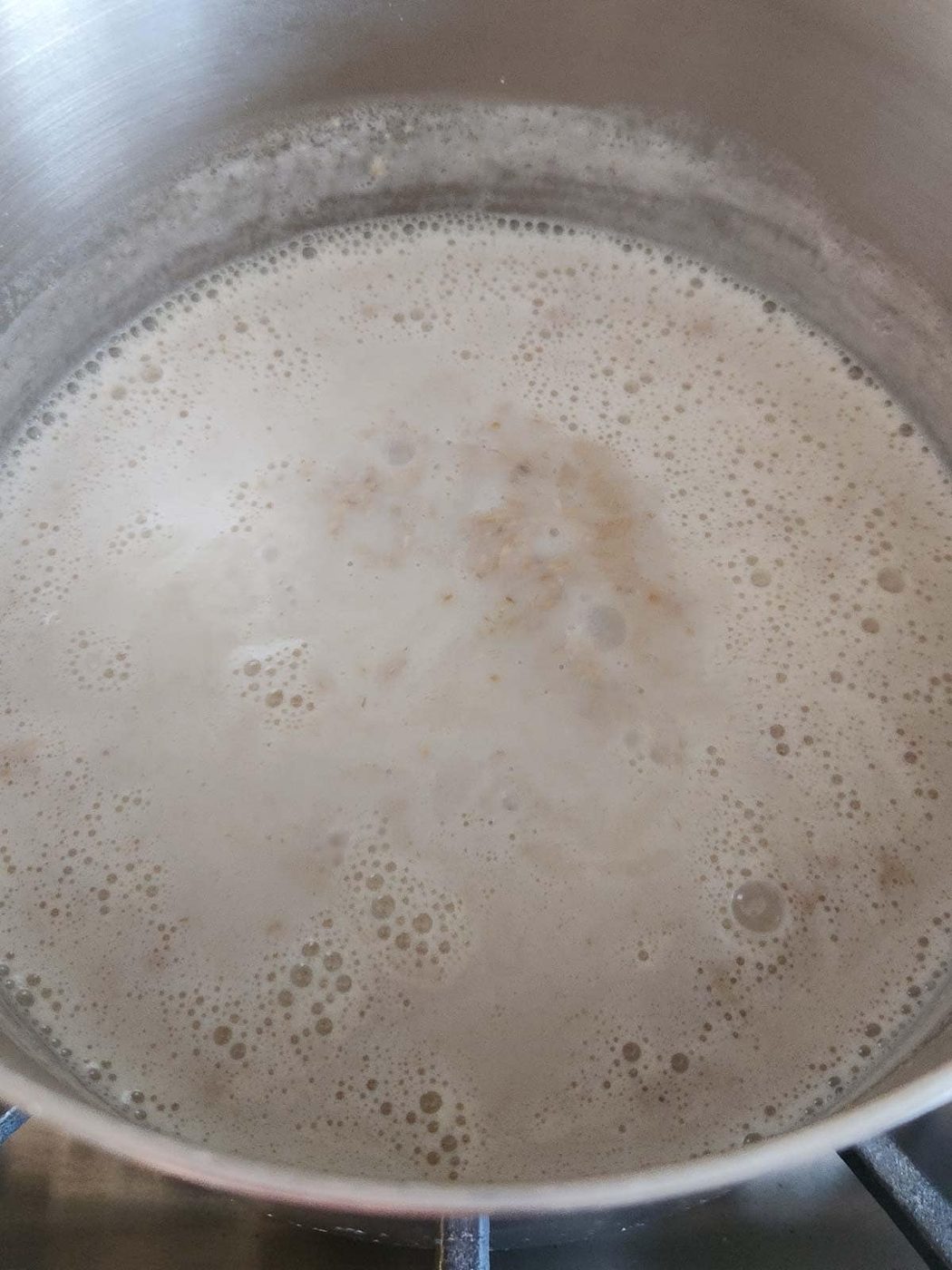 Oatmeal cooking in a stainless steel pot.