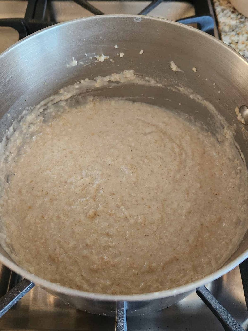 Cooked creamy oatmeal in a pot on the stove.
