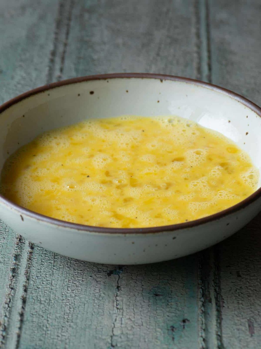 Whisked eggs is a beige bowl.