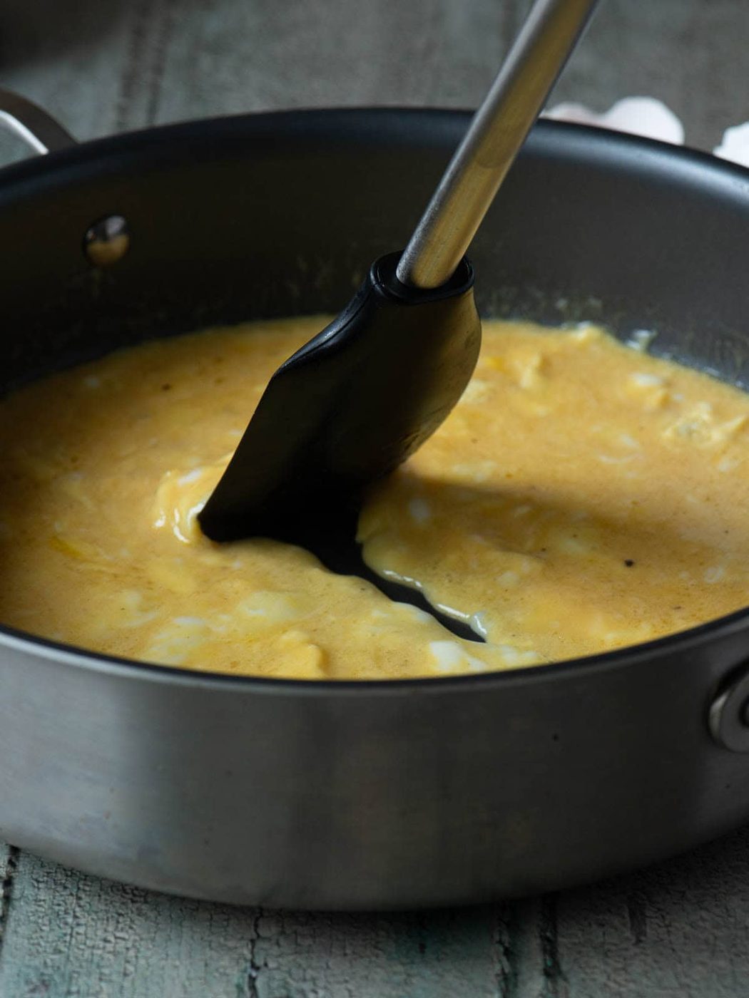 Scrambled eggs being mixed with a spatula in a skillet.