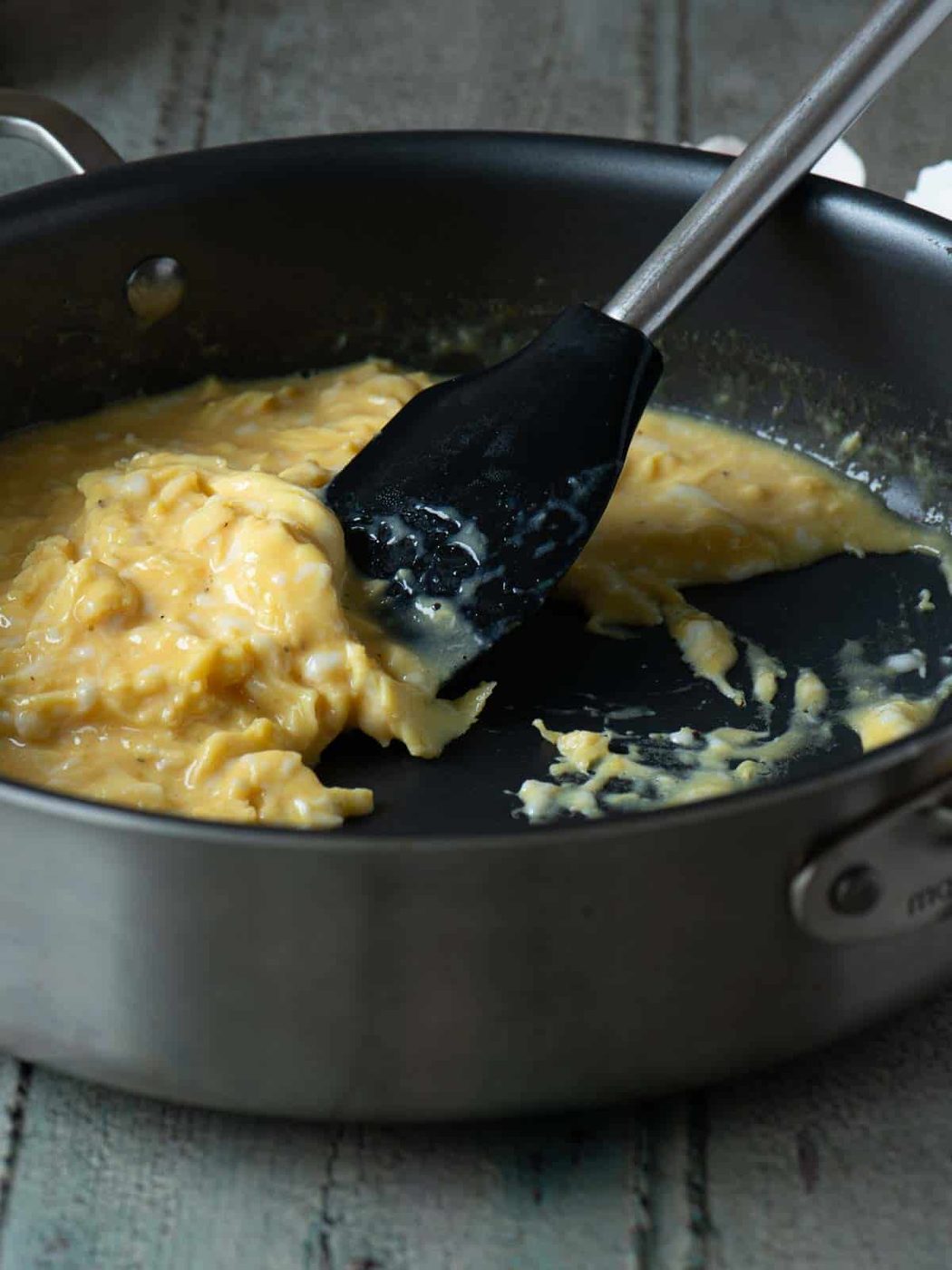 Scrambled eggs being mixed in a skillet with a spatula.