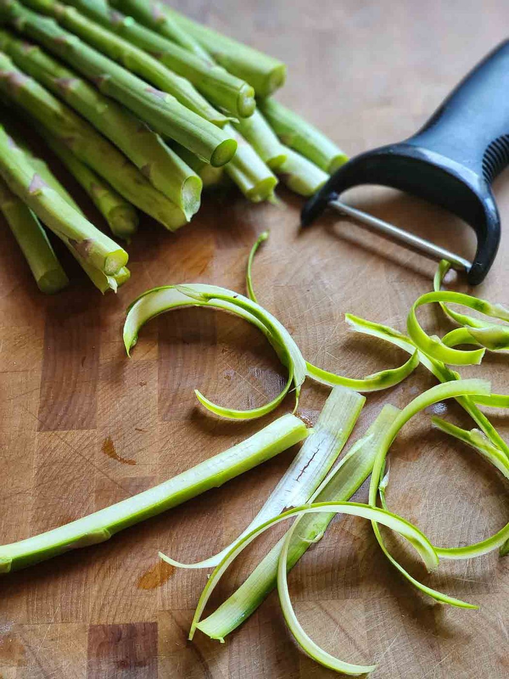 Showing how to shave asparagus using a peeler.