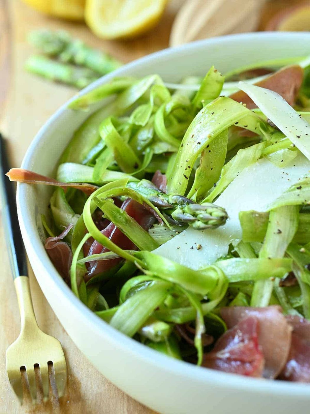 Close-up of shaved asparagus in a white bowl.