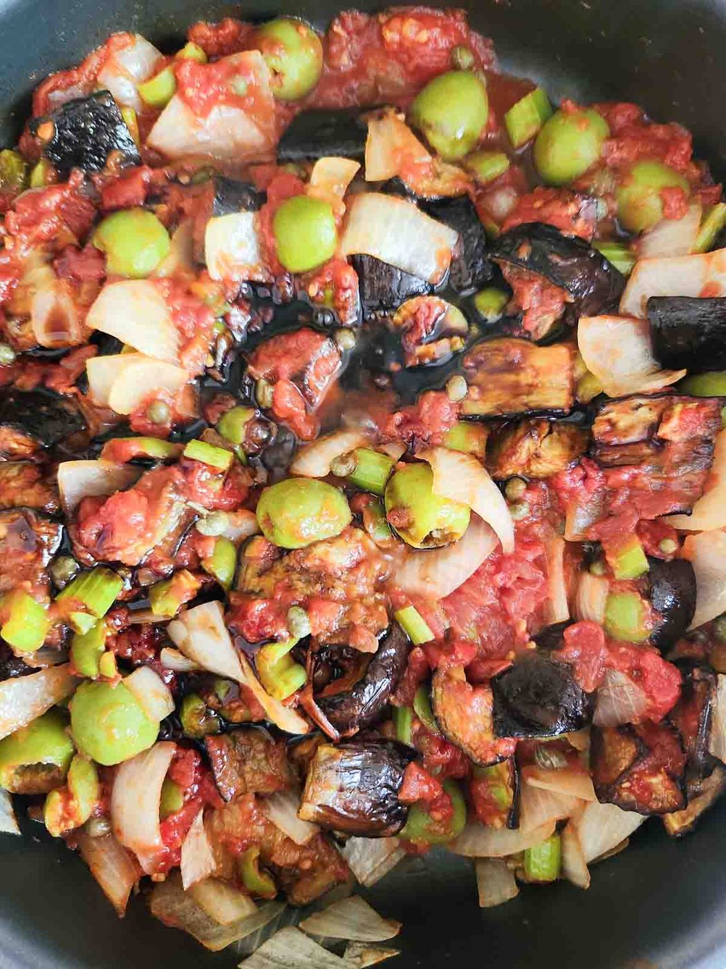 Caponata ingredients mixed in a pan.
