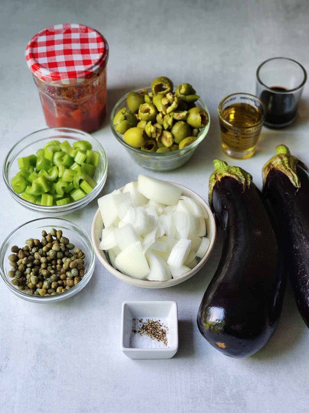 Ingredients for Sicilian caponata on a grey surface.