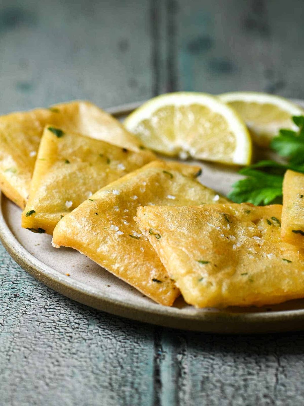 Chickpea fritters in a white plate with lemon wedges.