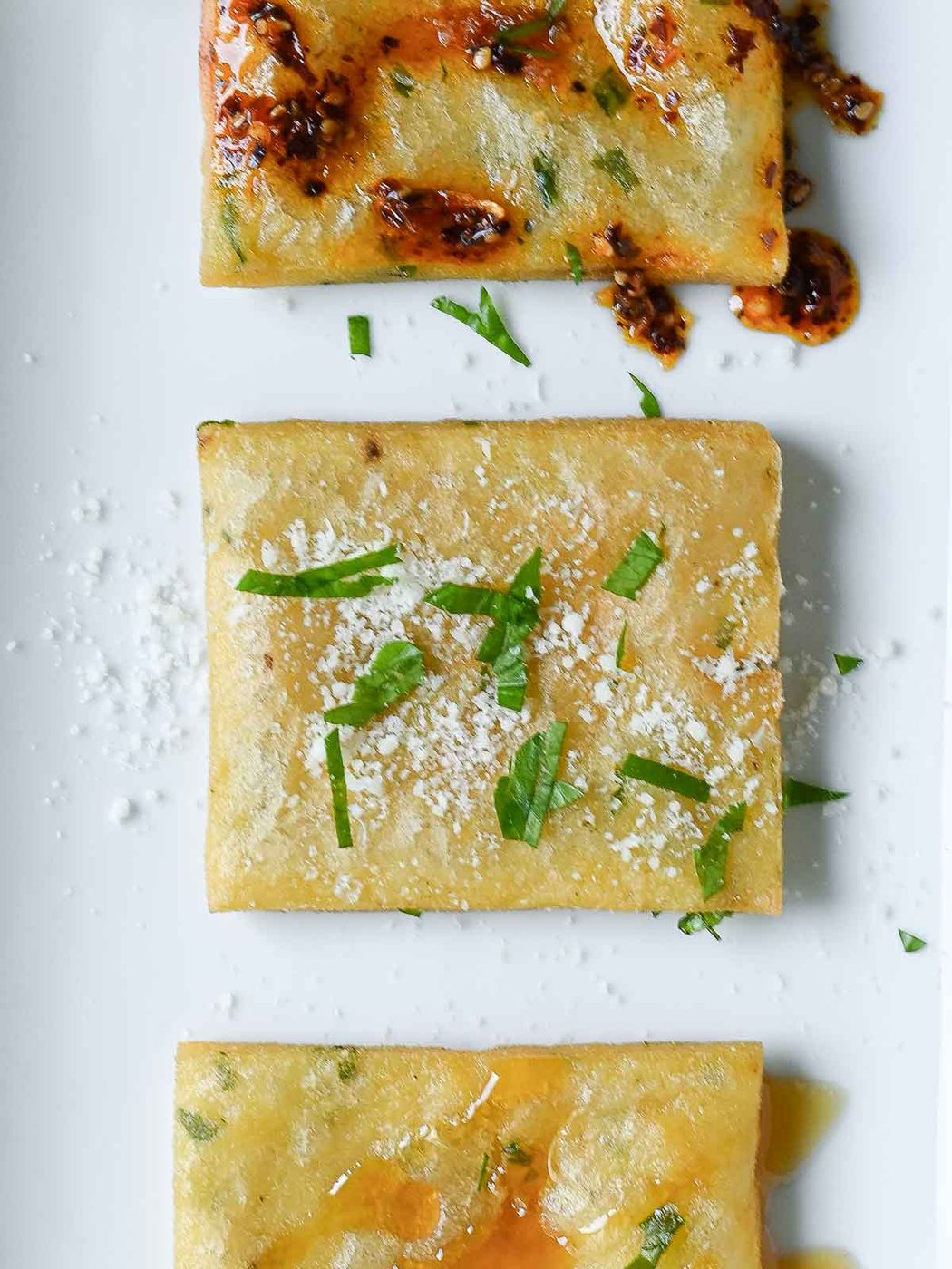 Three square pieces of chickpea fritters on a white plate.