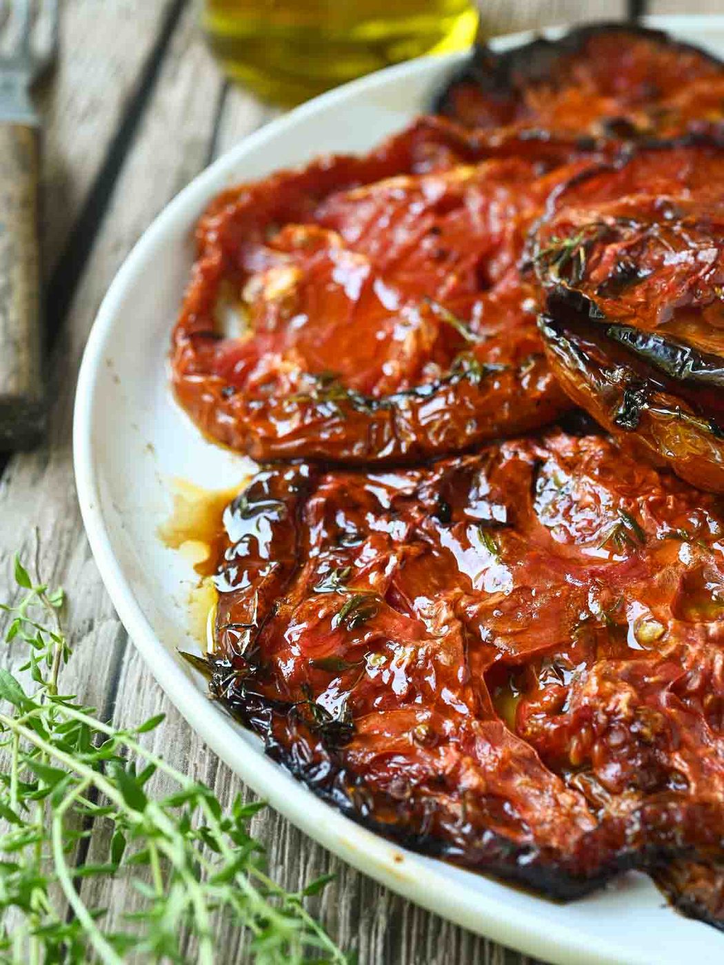 Close-up of roasted tomatoes with oil and thyme.