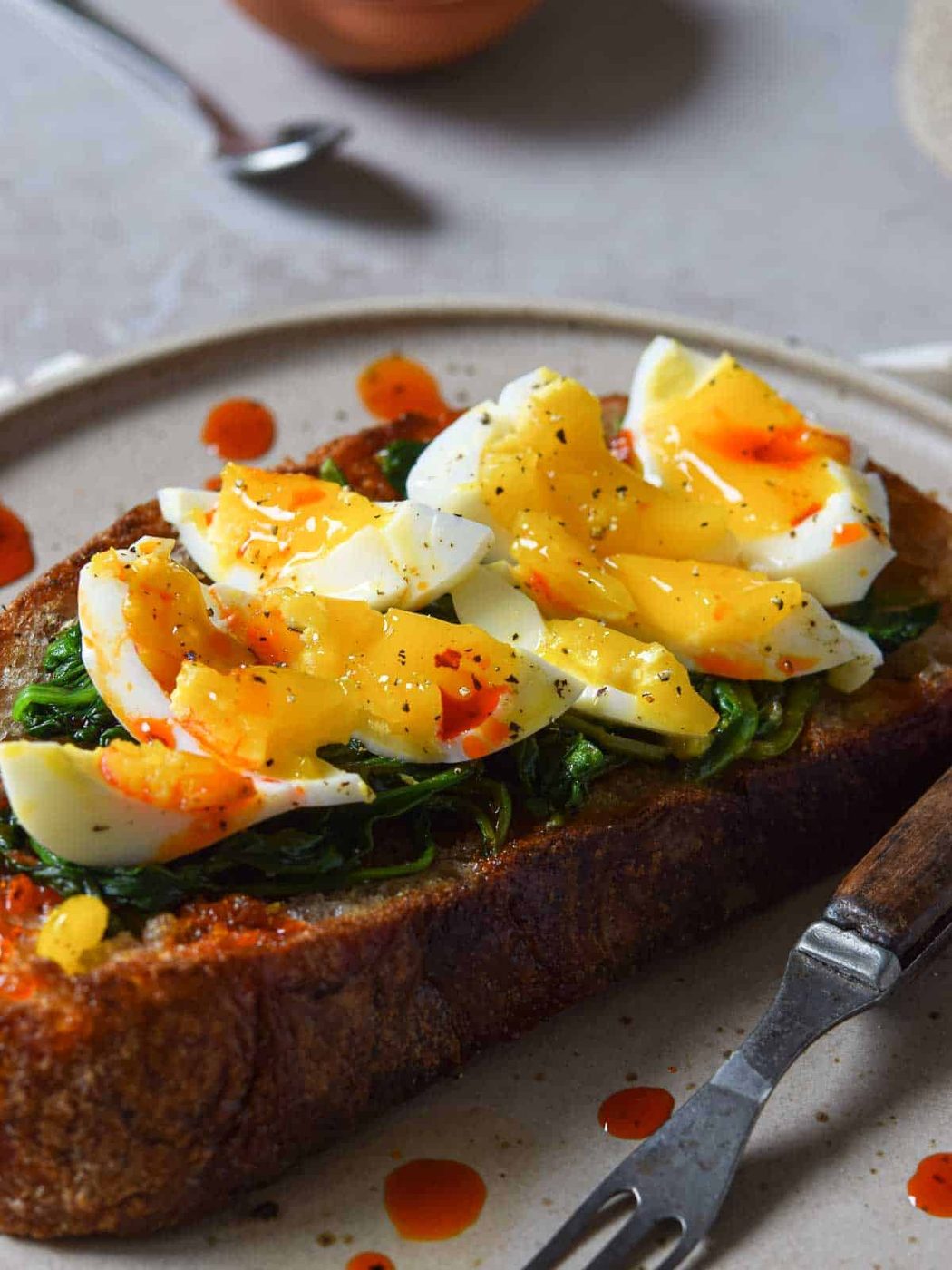 Close-up of smashed eggs on toast with seasoning.