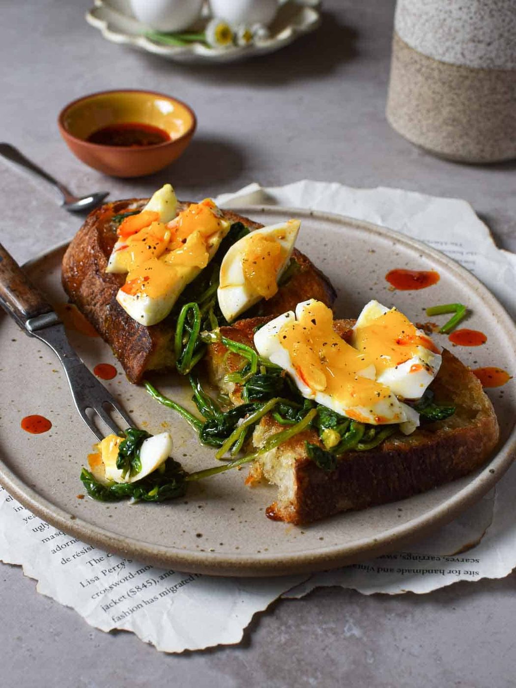 Smashed eggs on toast cut in half with a fork that has a piece of egg on it.