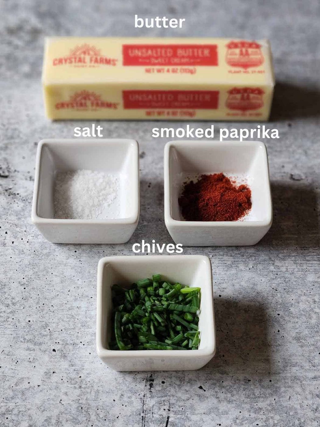 Ingredients for chive butter on a grey surface.