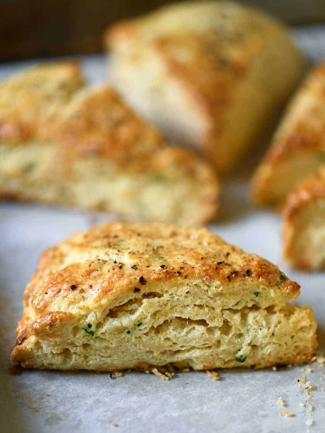 Close-up of a savory scone from the side on parchment paper.
