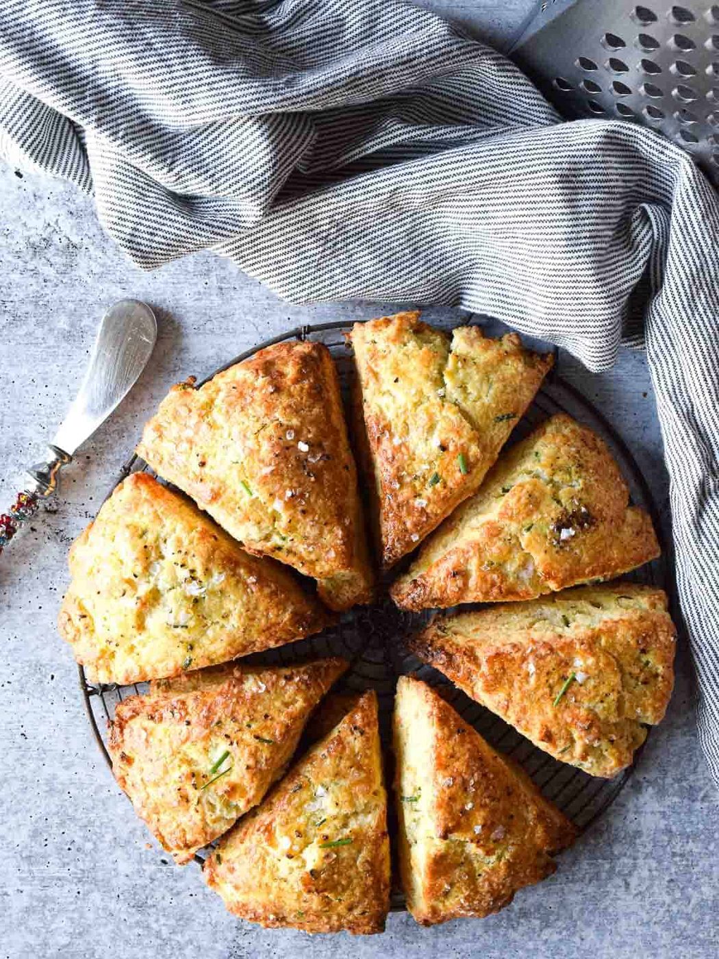 Overhead view of smoked gouda and chive scones cut in eight triangles on a concrete gray background.