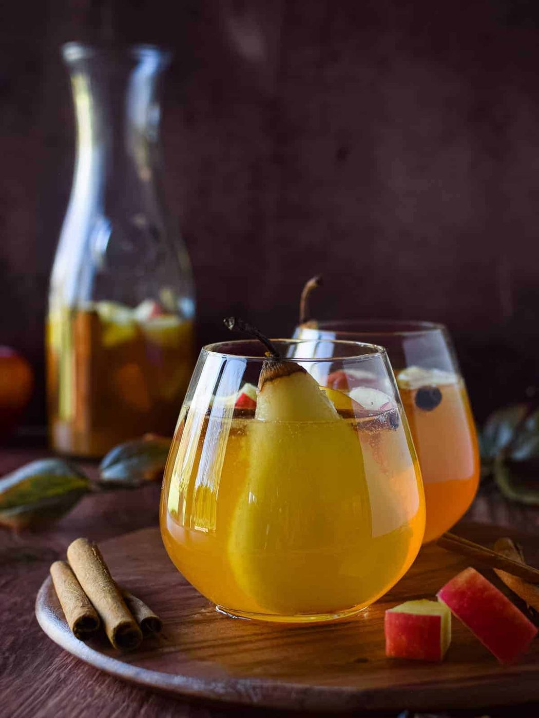 Apple and pear sangria in a glass on a wooden board.
