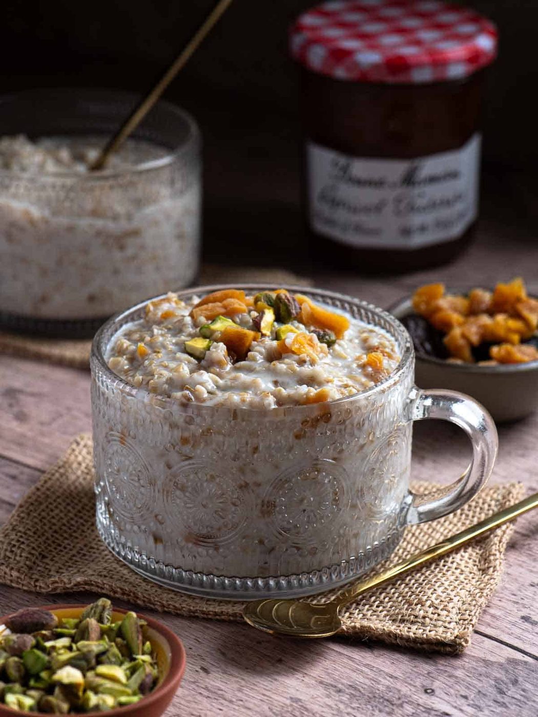 Creamy oatmeal with apricots and pistachios in a clear bowl.