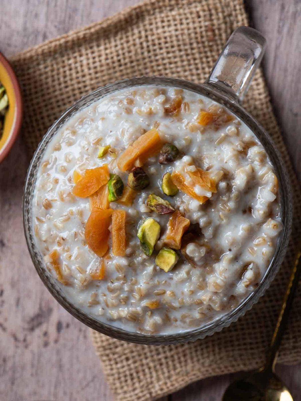 Overhead of apricot oatmeal in a bowl on a piece of burlap.