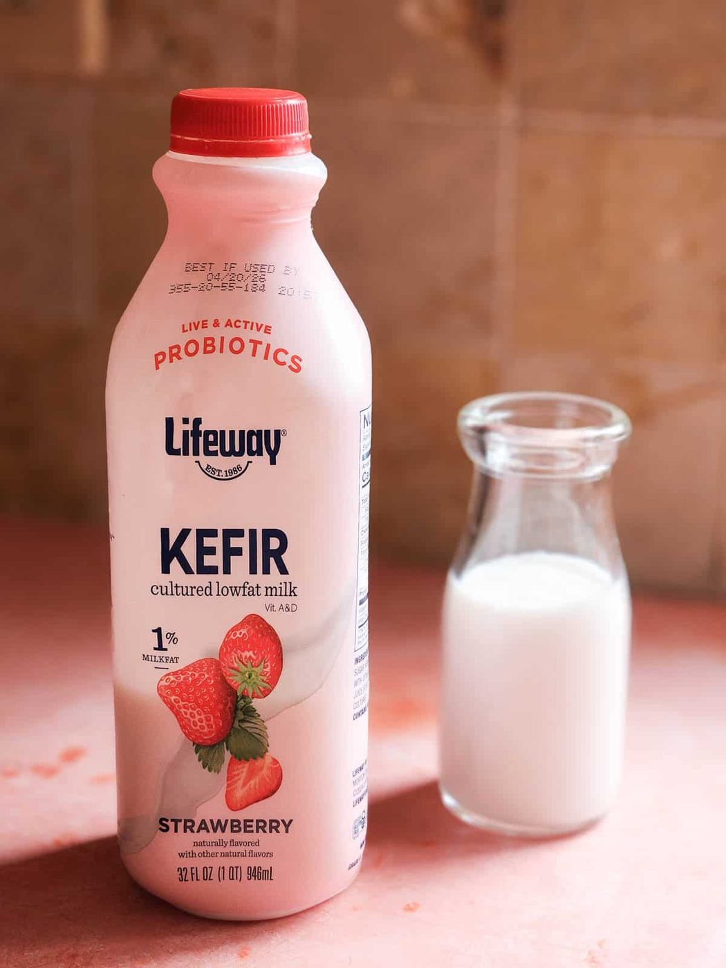 A bottle of Strawberry Kefir on a pink surface.