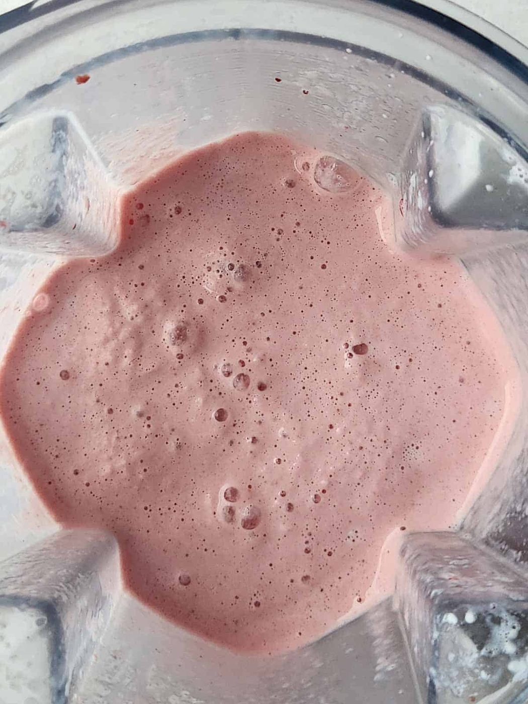Overhead of a blended pink smoothie in a blender.