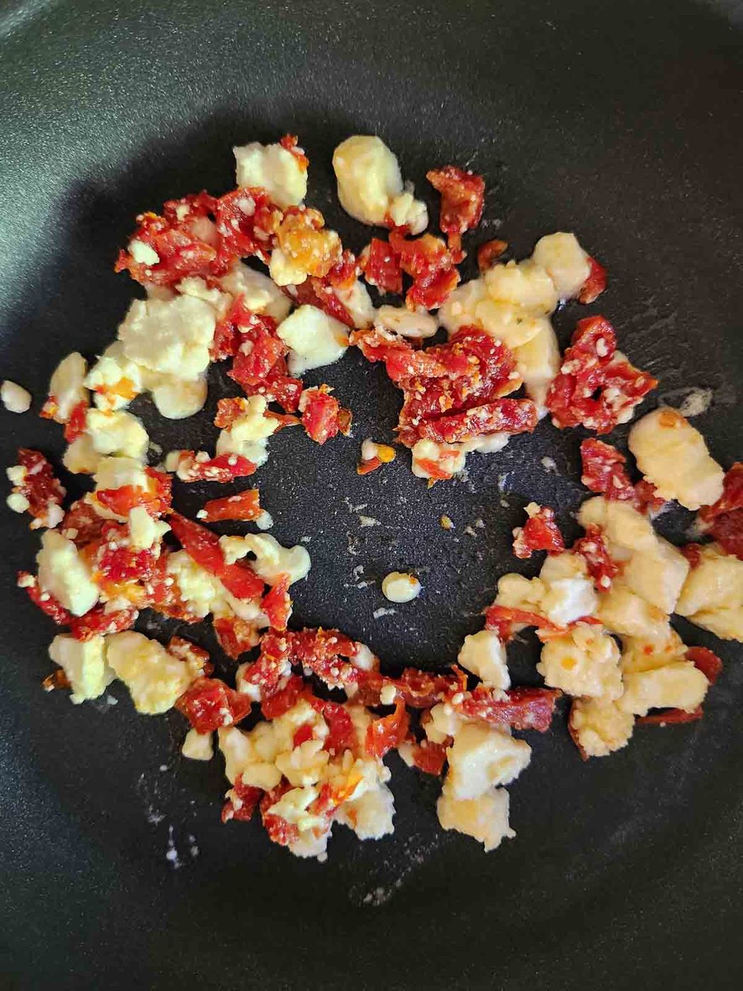Sun-dried-tomatoes and feta in a skillet.