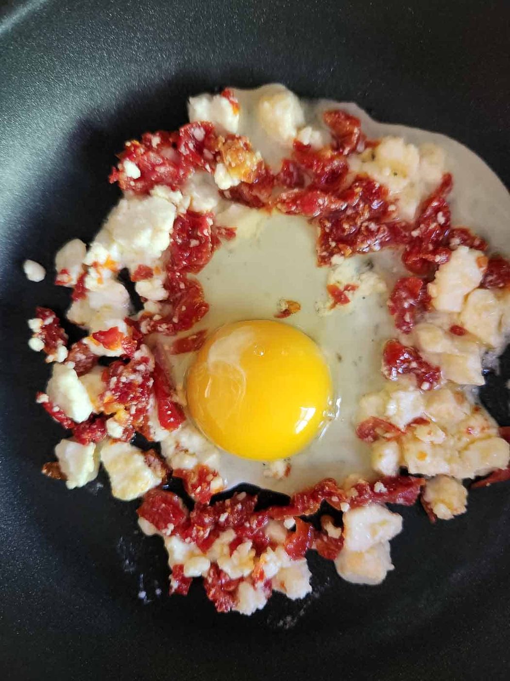 Tomatoes, feta and an egg in a skillet.