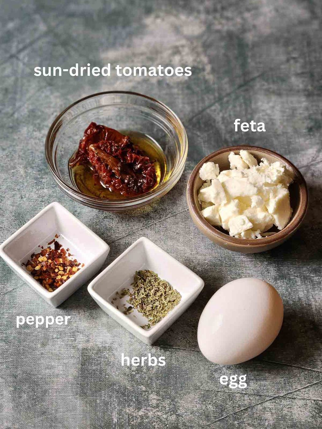 Ingredients for feta fried eggs on a grey surface.