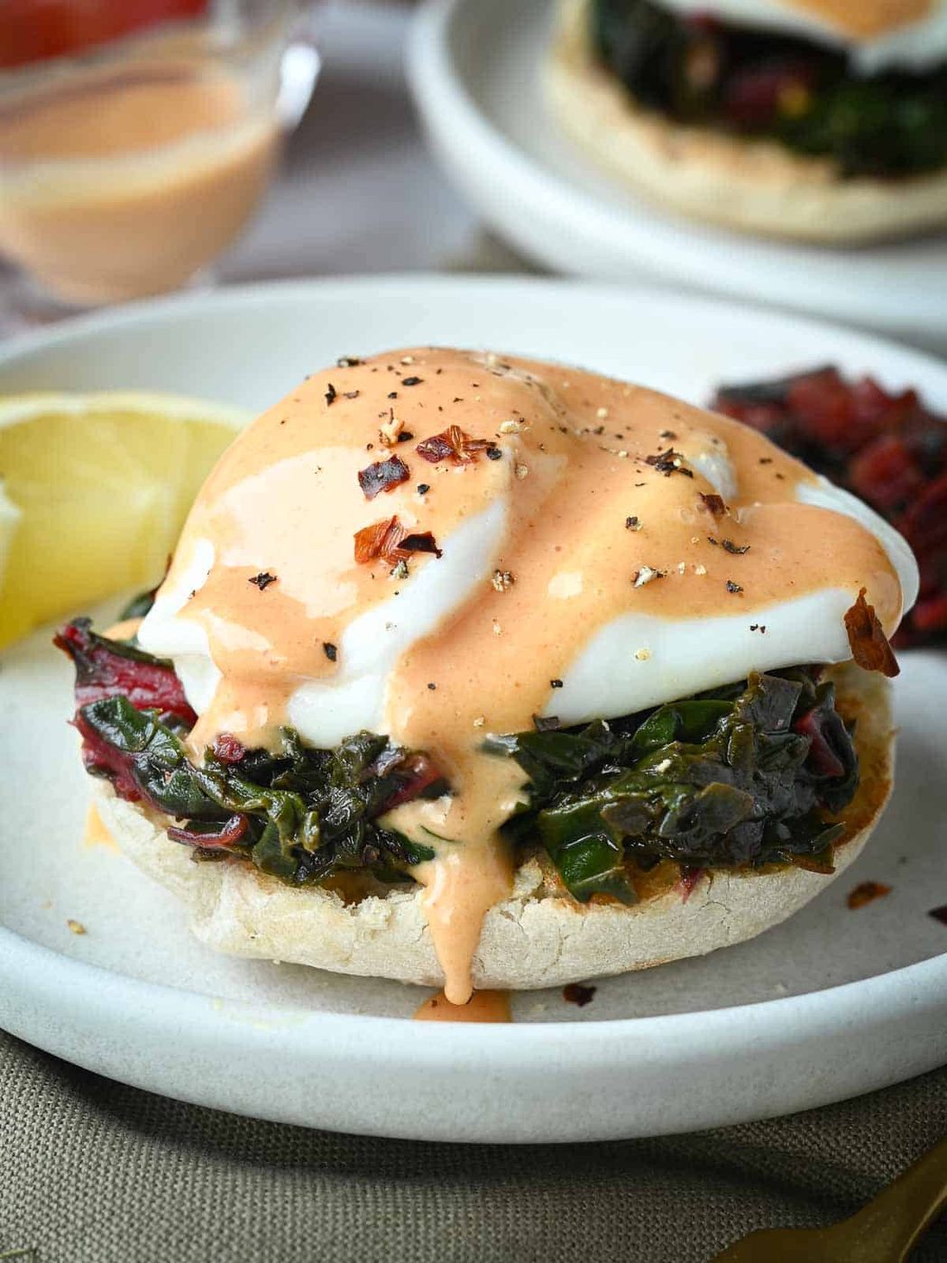 Swiss chard eggs Florentine on a white plate with a lemon in the background.
