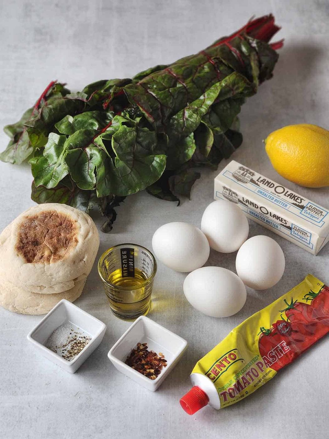 Ingredients for Swiss chard eggs Florentine on a grey surface.