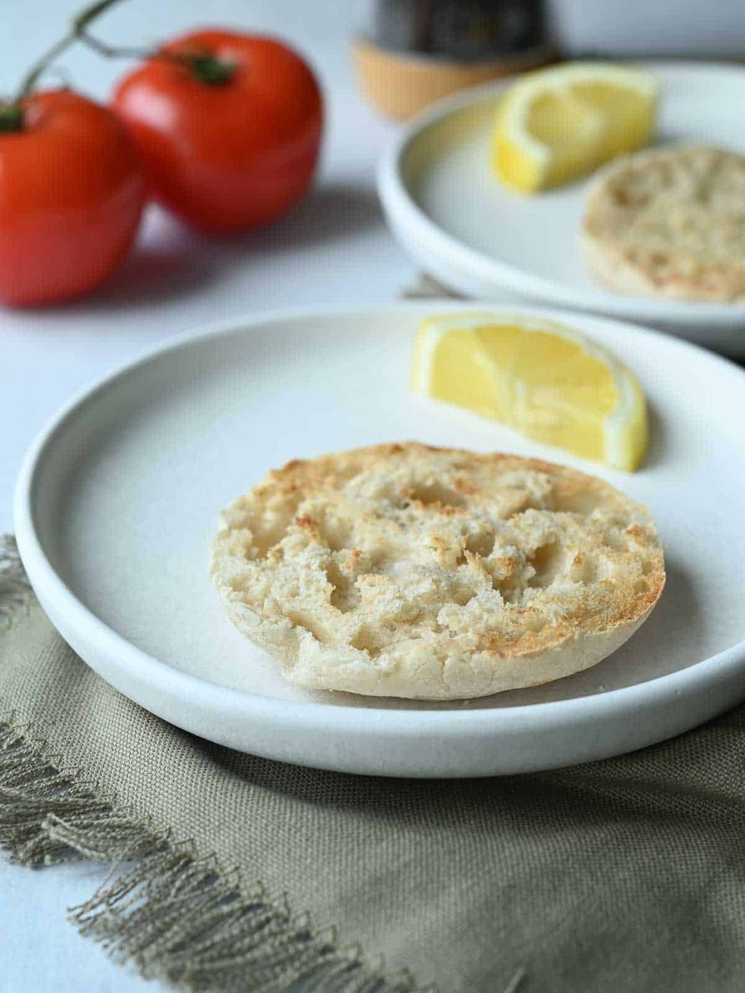 Two white plates with English muffins on them.