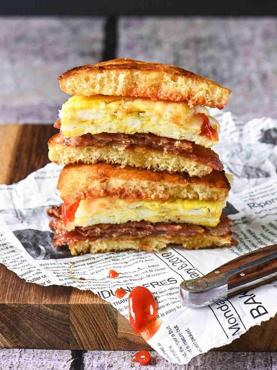 Stacked breakfast sandwiches, vut showing the insides on a board.