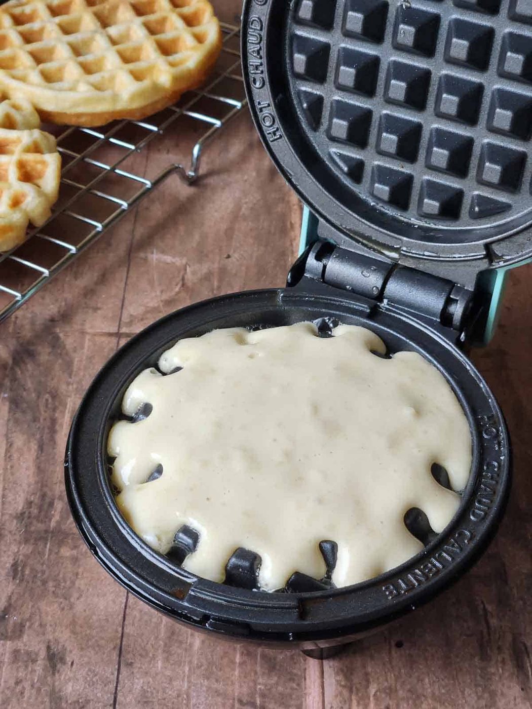 Waffle batter on cooking on a mini waffle maker.