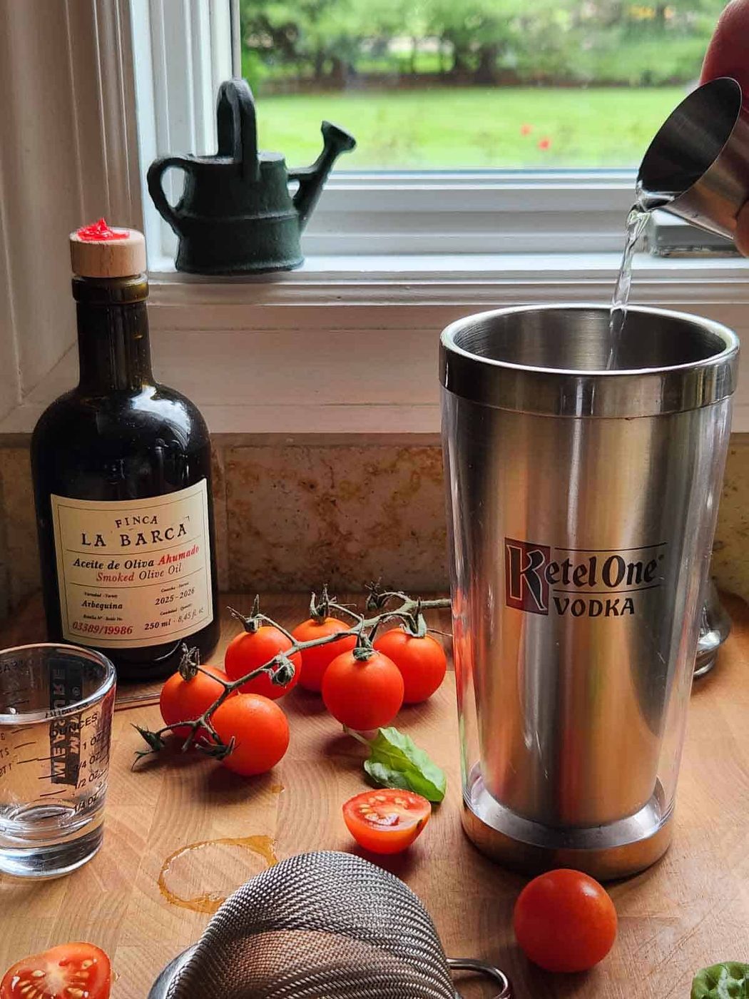 Vodka is being poured into a cocktail shaker on a wooden board with other cocktail ingredients.