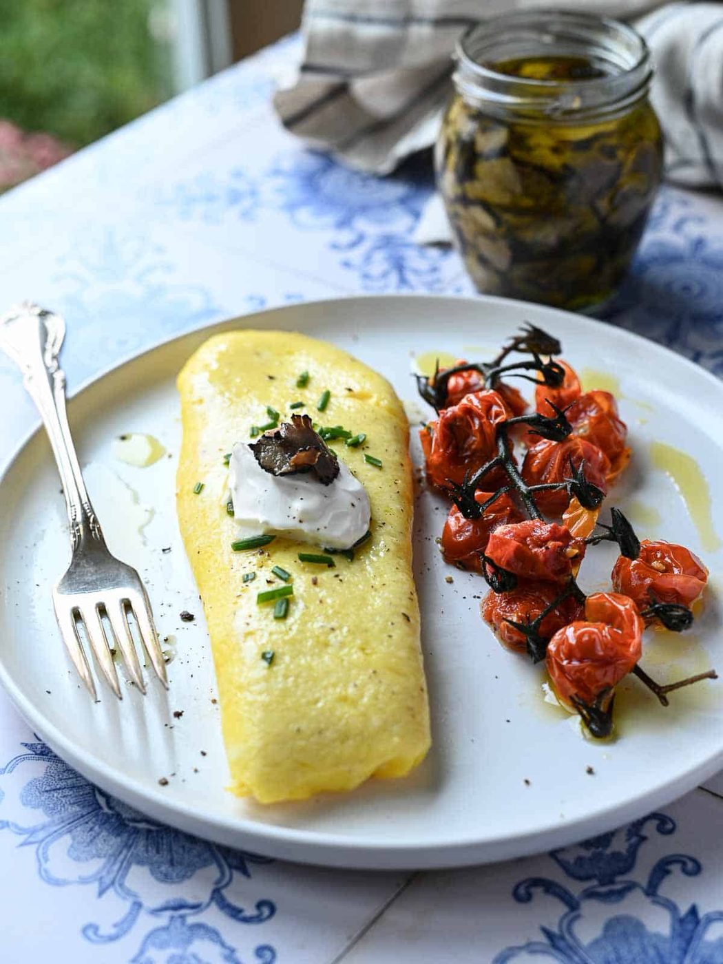 Angled view of an omelet with truffles and creme fraiche on a white plate.