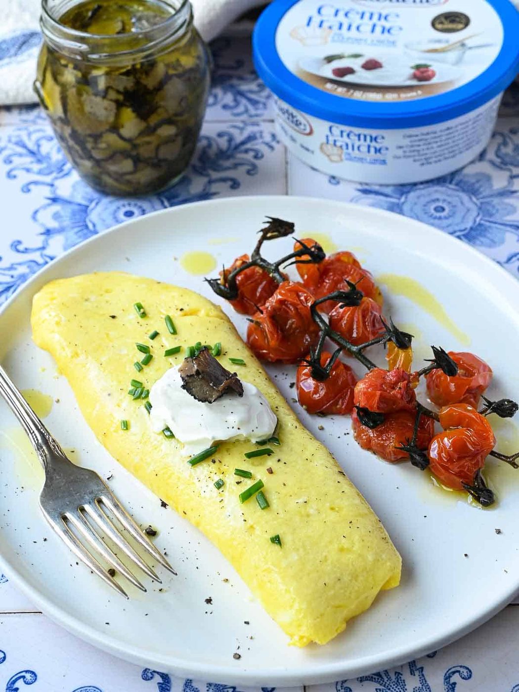 Truffle omelet on a white plate with tomatoes on the side.