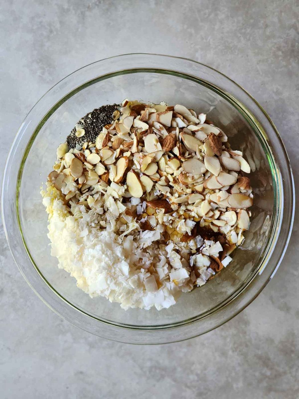 Overhead of granola ingredients in a clear bowl.